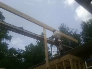 Carpenter setting a ridge beam over a new addition frame — Ice Dam Removal by Roofing Brothers in Garfield
