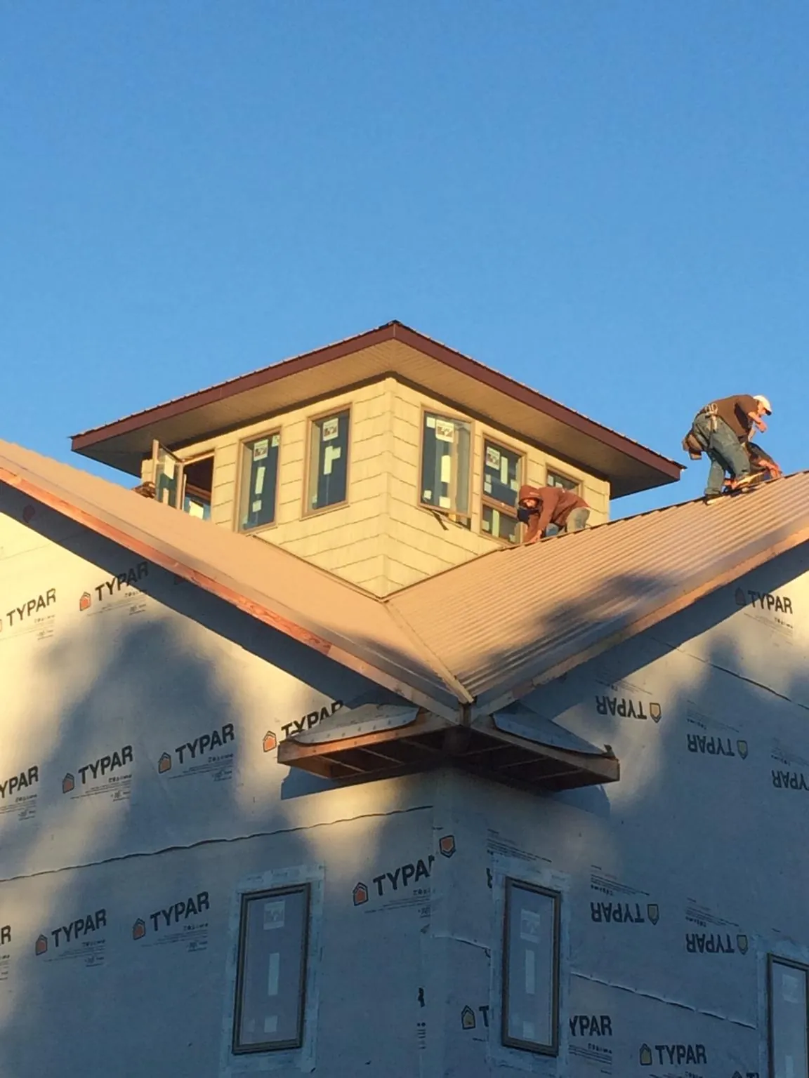 Roofers working around a rooftop cupola on a new metal roof at sunset — Roof Waterproofing in Garfield by Roofing Brothers